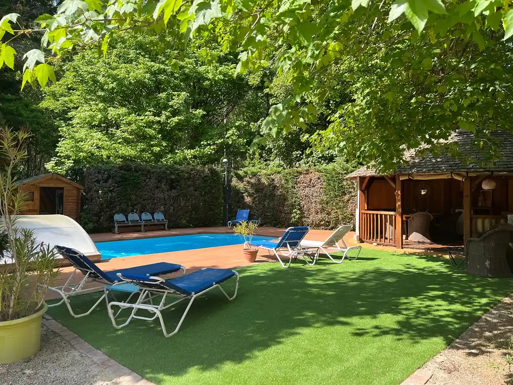 La piscine et le jardin, transats à l'ombre des arbres.